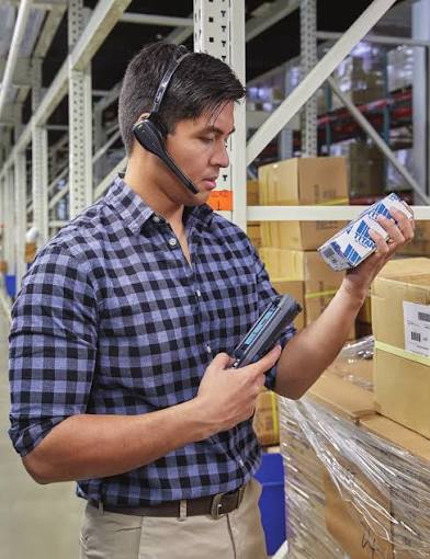 Worker using voice headset while scanning a product barcode in a warehouse
