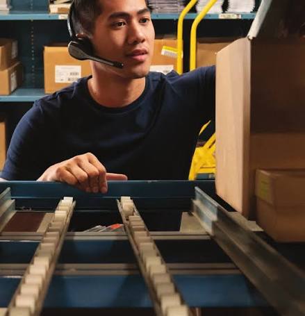 Warehouse associate with voice headset managing inventory from racking